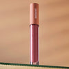 Lifestyle shot Minori Lip Gloss - Juneberry (3.5 ml) sitting on glass shelf