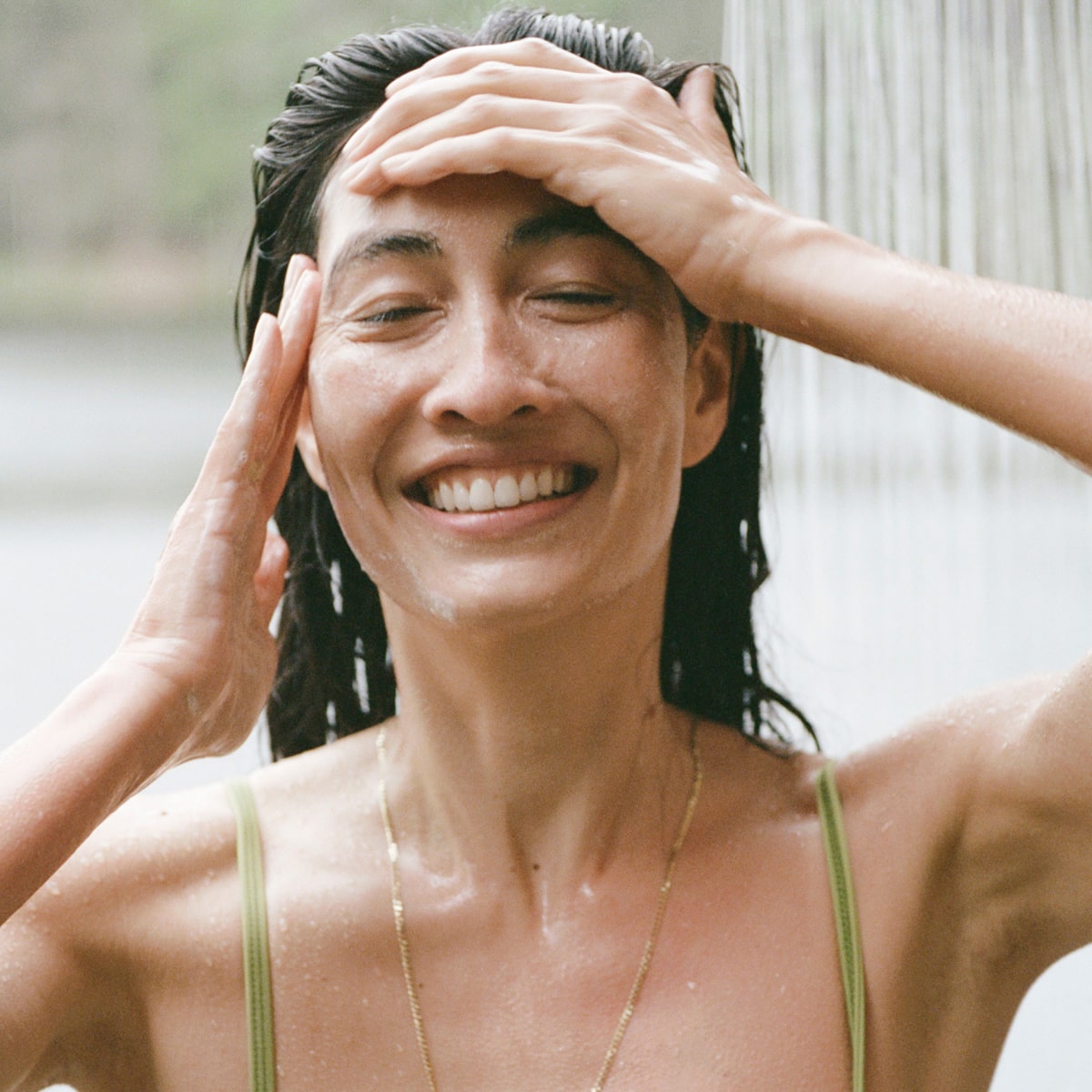 Ursa Major Go Easy Daily Shampoo (10 oz)  - model shown rinsing hair with product. 