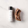 Essential Parfums Bois Imperial Hair & Body Mist (100 ml) - product shown next to wood. 
