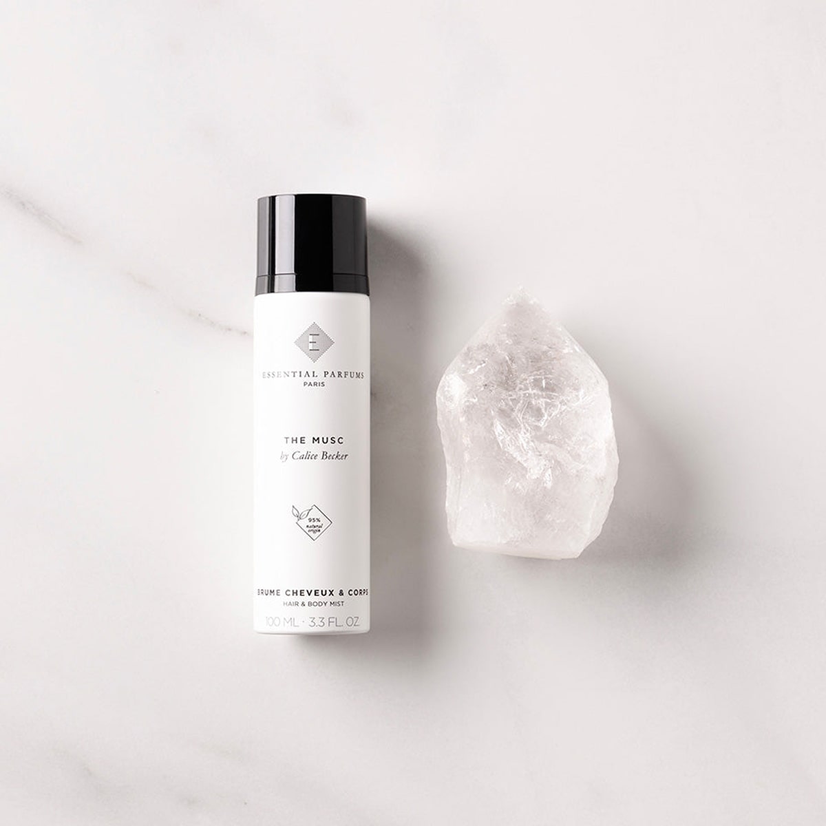 Essential Parfums The Musc Hair & Body Mist (100 ml) - product shown next to gemstone. 