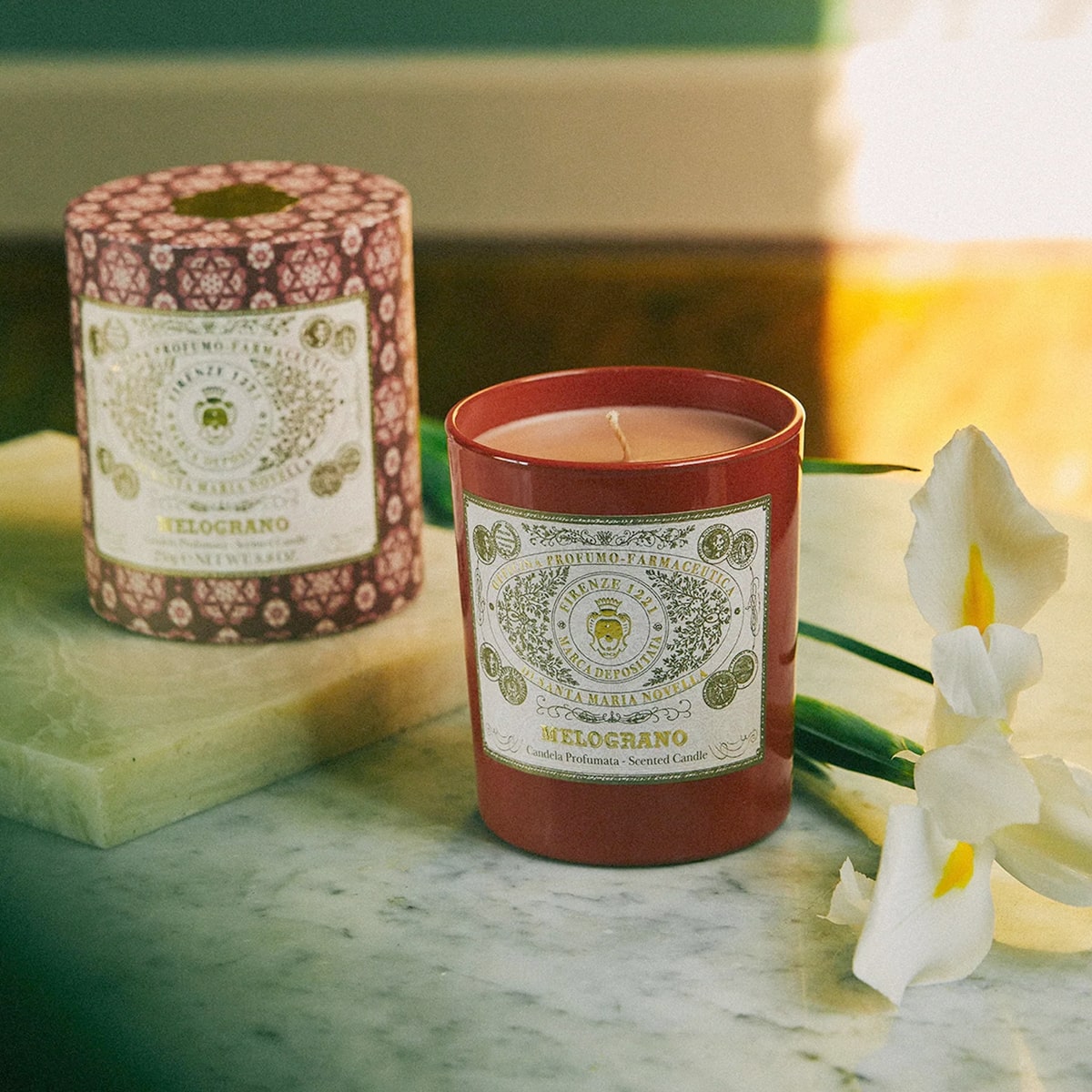 Lifestyle shot of Santa Maria Novella Melograno Scented Candle (250 g) with white flowers next to candle