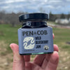 Pen & Cob Farm Wild Blueberry Jam (9 oz) - product shown being held up by hand in front of green forest area. 