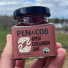 Pen & Cob Farm Apple Cardamom Jam (4.4 oz) - product shown being held in front of greenery. 