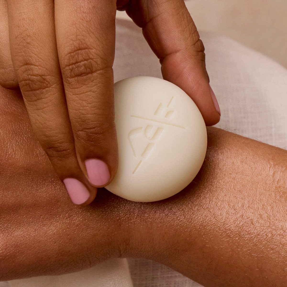 Model applying a Kate McLeod Mini Body Stone to back of wrist