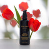 Figaro Apothecary Sheer Botanical Body Oil (3.4 oz) with red tulips in the background