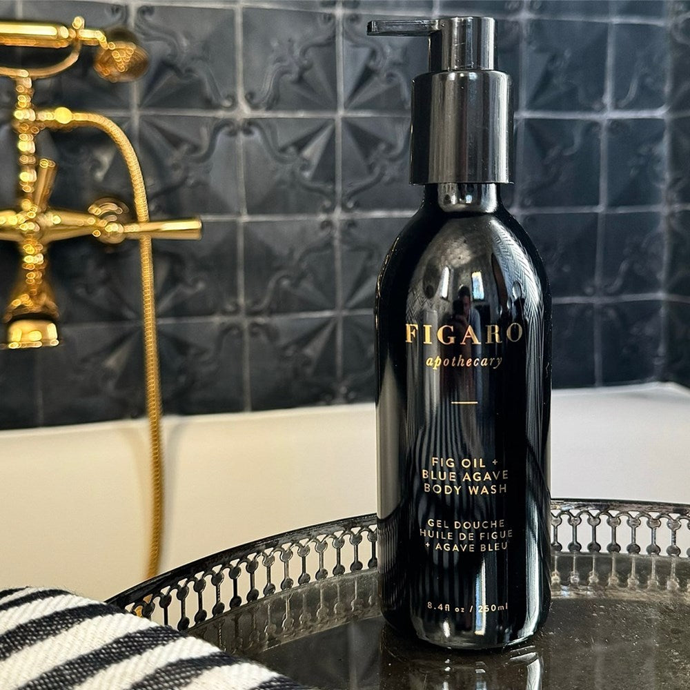 Figaro Apothecary Fig Oil + Blue Agave Body Wash (8.4 oz) shown on tray with a tiled wall and gold faucet in the background.