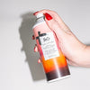 R+Co Sun Catcher Power C Styling Spray (5 oz) - product being sprayed against a white background. 