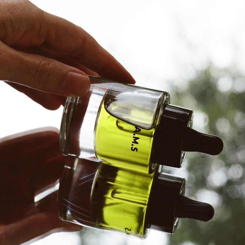 Activist A.M.S. Green Botanical Serum (1 oz) - product shown on reflective surface. 