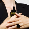 Activist A.M.S. Green Botanical Serum (1 oz) - product shown being held by model. 