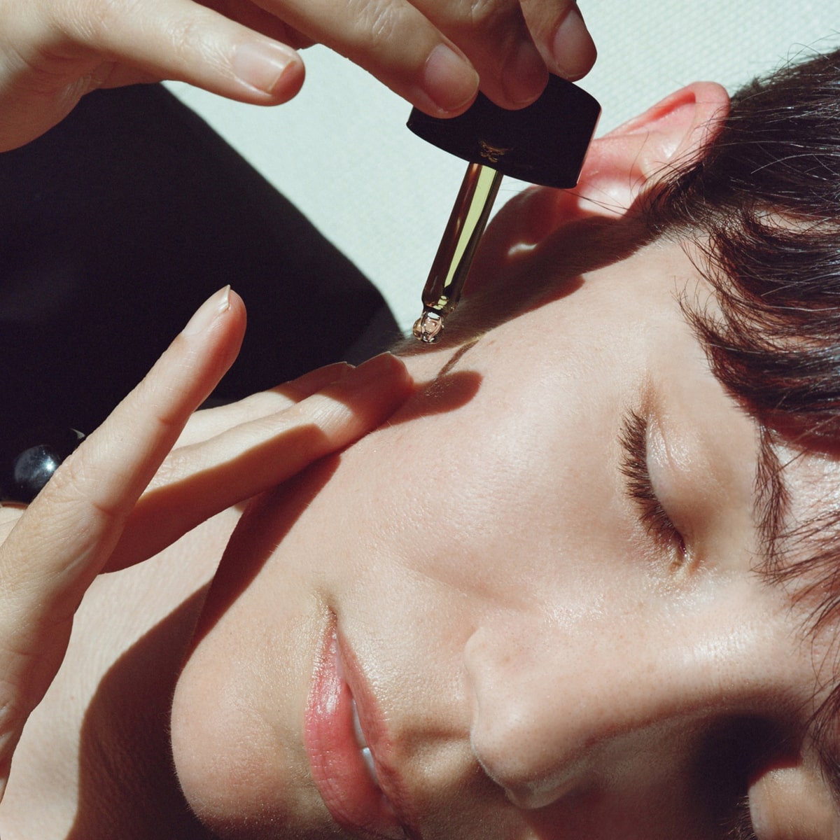 Activist A.M.S. Green Botanical Serum (1 oz) - product shown being applied on model. 