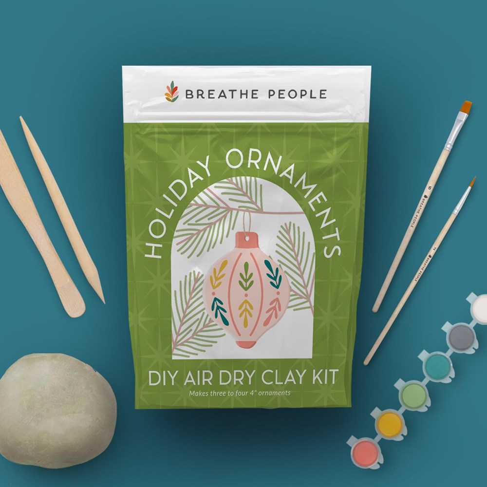 Breathe People DIY Air Dry Clay Kit - Make Your Own Holiday Ornaments (1 kit) - product shown on blue background with supplies around it. 