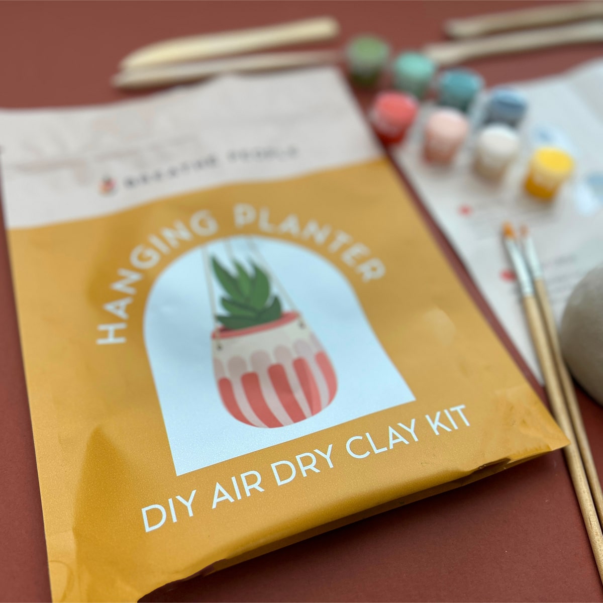 Breathe People DIY Air Dry Clay Kit - Make Your Own Hanging Plant Pot (1 kit) - product shown on maroon background. 