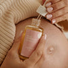 Minois Paris Mama Generous Body Oil (100 ml) - product shown being held by hands. 