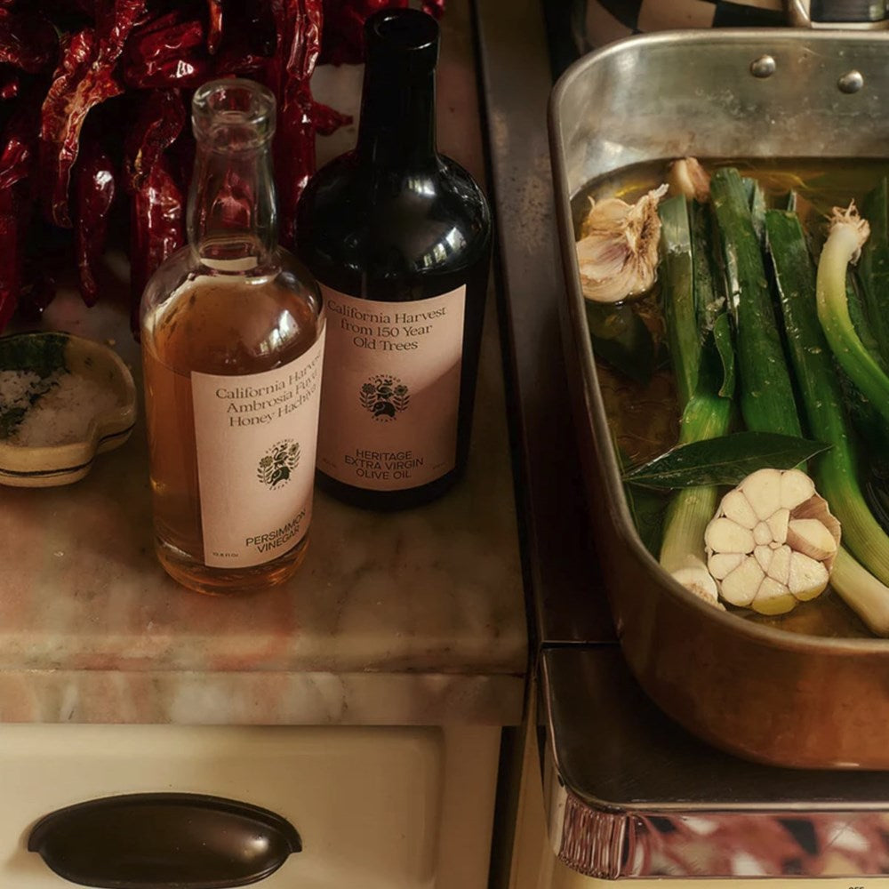 Flamingo Estate Organics Olive Oil and Fuyu Persimmon Vinegar Gift Box Set (2 pcs) - product shown next to cooking pan. 