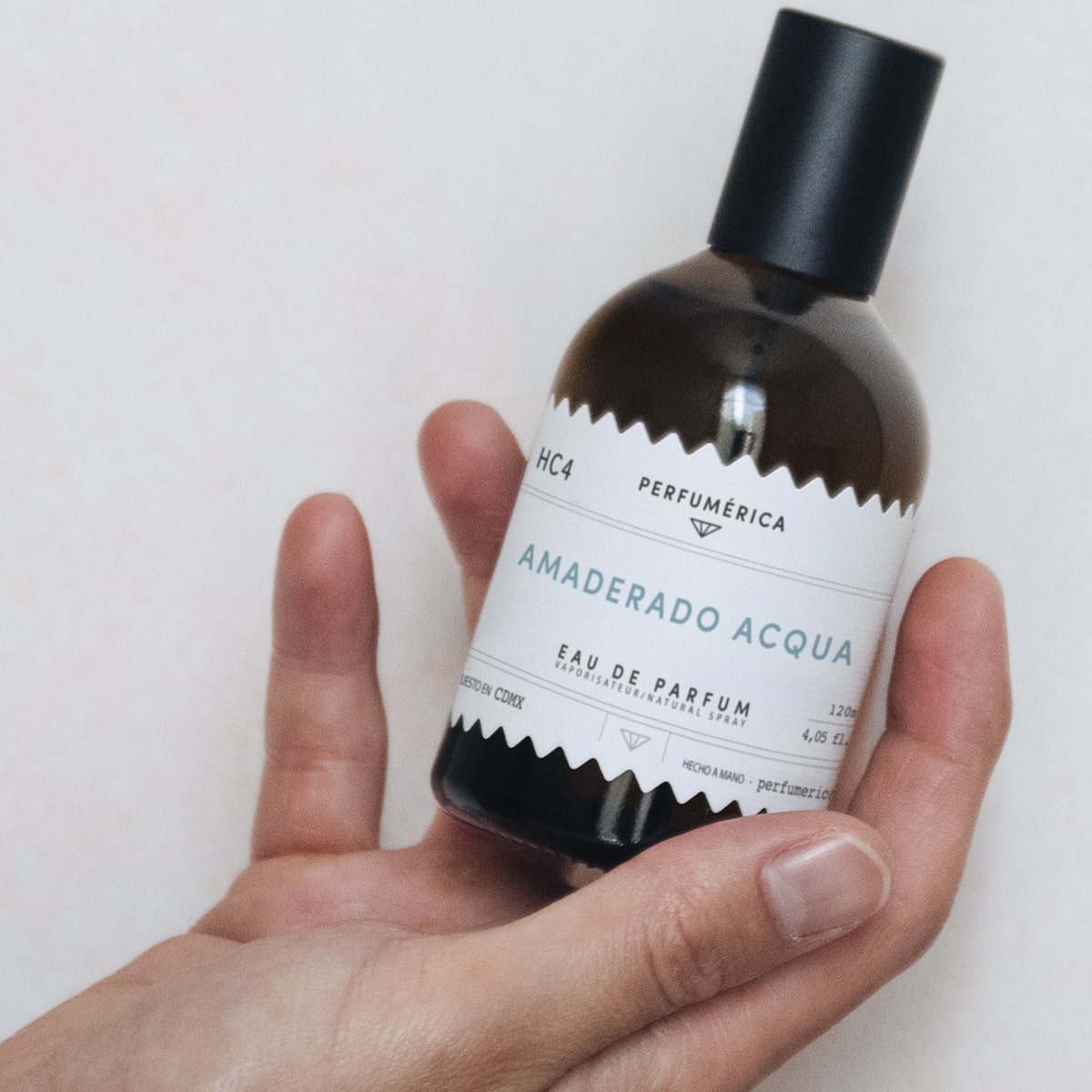 Perfumerica Amaderado Acqua Eau de Parfum (120 ml) - product being held. 