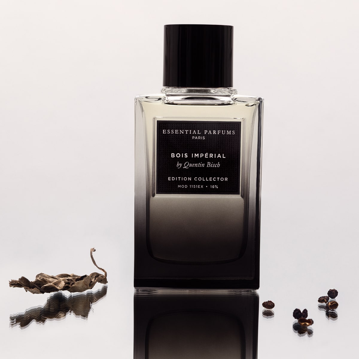 Essential Perfumes Bois Imperial Collector Edition by Quentin Bisch (100 ml) on a reflective surface with dried leaves and berries.