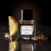 Essential Perfumes Nice Bergamote Extrait de Parfum by Antoine Maisondieu (50 ml) on a dark surface with various ingredients in the foreground.