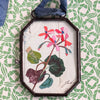 Maris Mirum Small Locket - Geranium No. 1 (1 pc) with green and white patterned paper in the background