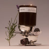 NETTE French Chocolate Scented Candle (11 oz) - product shown balancing on top of metal bowls with a flower and chocolate. 