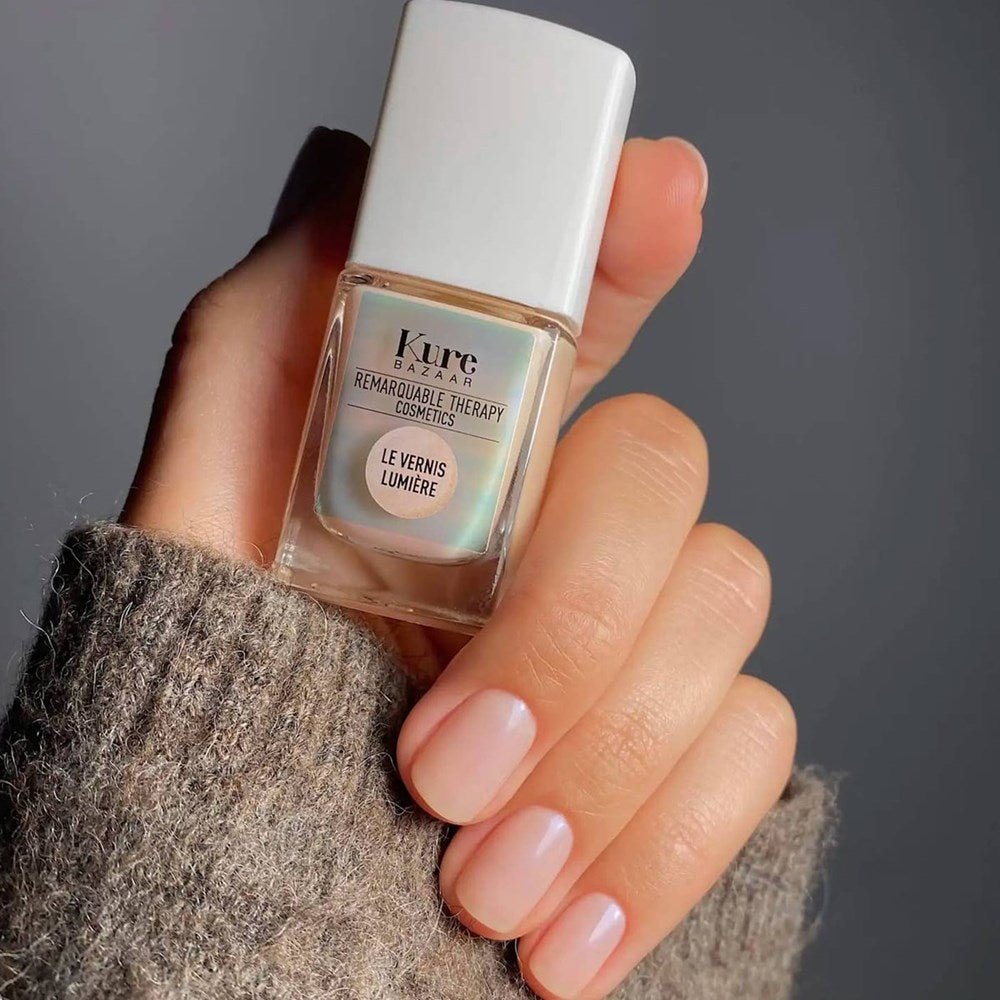 Kure Bazaar Vernis Lumière - Illuminateur Beige (10 ml) - product shown being held up. 
