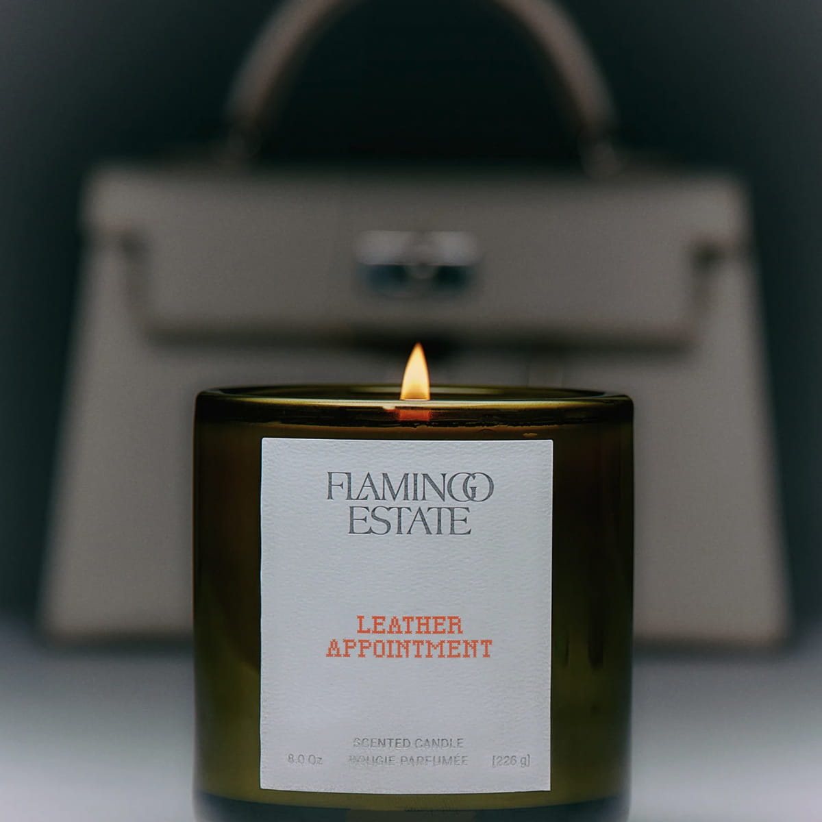 Flamingo Estate Leather Appointment (226 g) - product shown in front of leather bag.