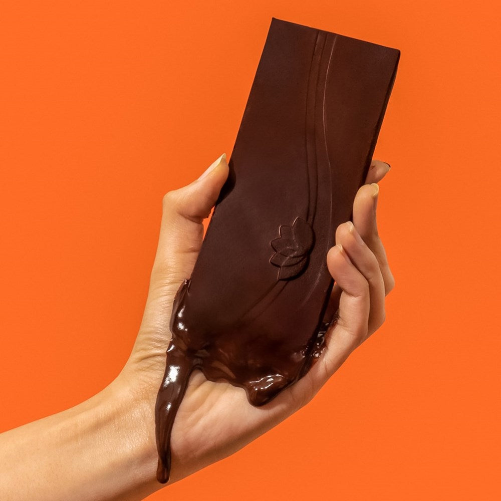 Hand holding Elements Raspberry Chocolate Bar (1.8 oz) against an orange background