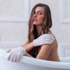 Woman in a bathtub wearing and using Daily Concepts Daily Exfoliating Gloves (1 pair)