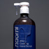 Bottle of Naomi After-Cooking Hand Scrub - Bergamot & Black Pepper Hand Wash (500 ml) with scrub coming out of pump and on bottle on a gray background