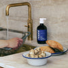 Lifestyle shot of Naomi After-Cooking Hand Scrub - Bergamot & Black Pepper Hand Wash (500 ml) on kitchen counter with shelfish in the foreground