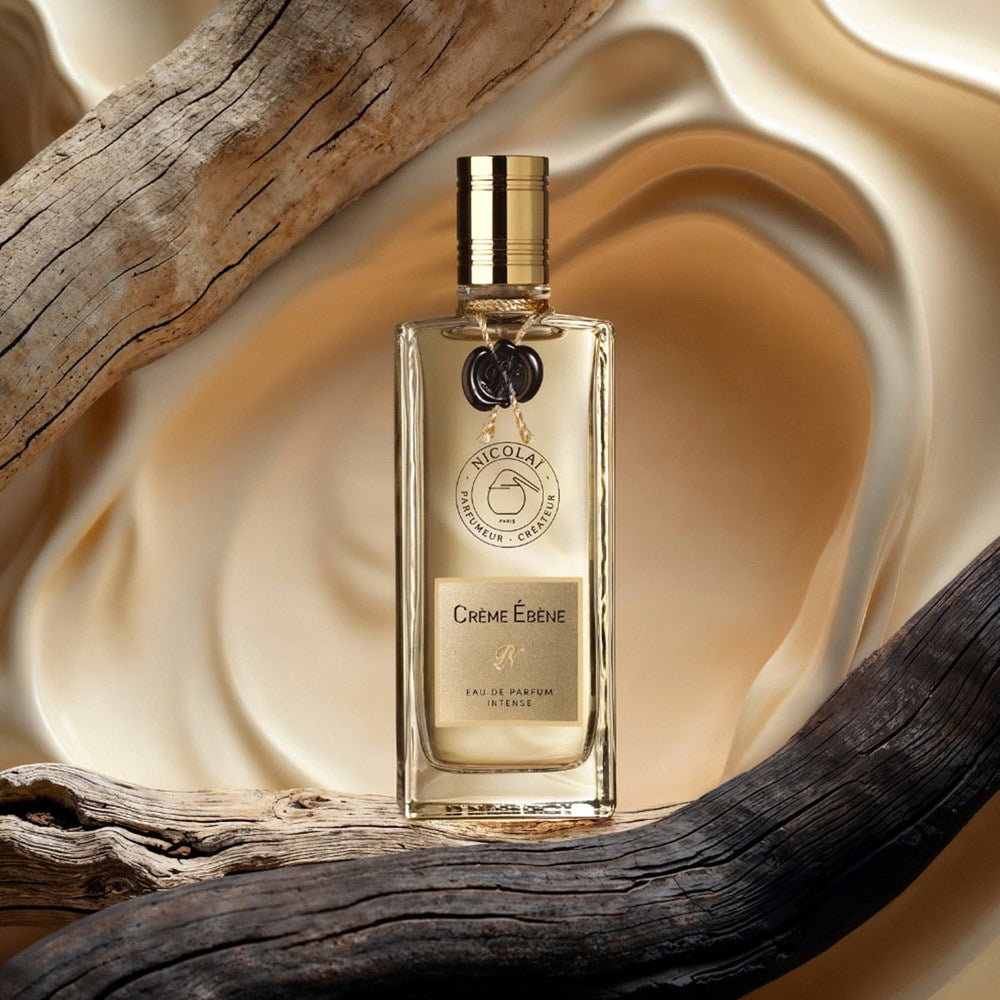 Lifestyle shot of Parfums de Nicolai Creme Ebene Eau de Parfum (100 ml) sitting on a piece of wood