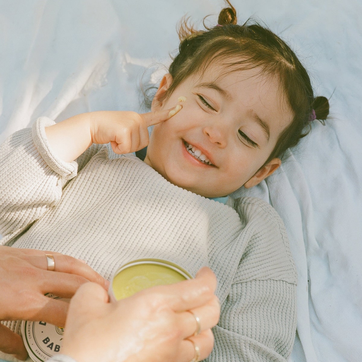 Dr. Max’s Baby Balm (3.3 oz) - product shown being applied to child's face.