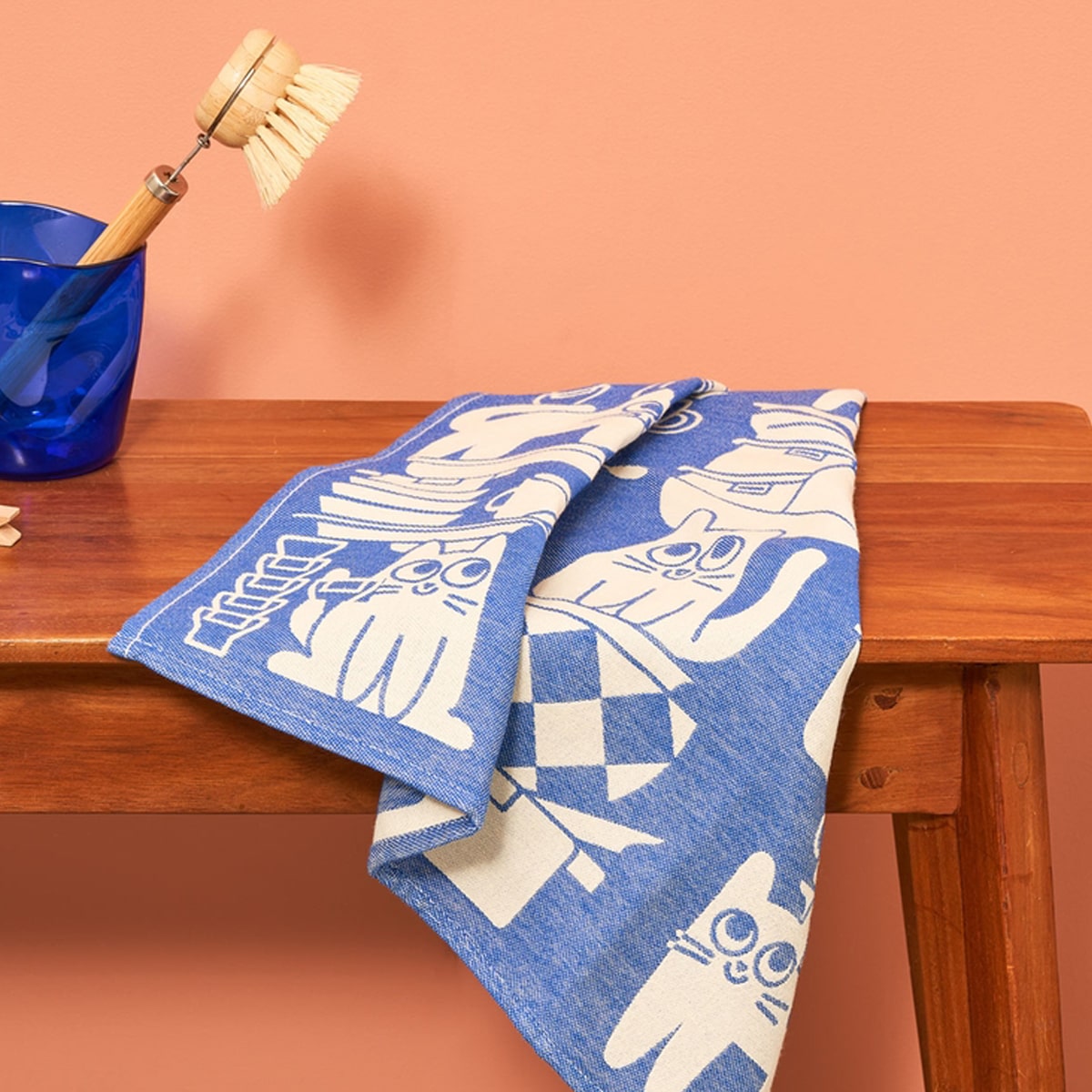 Lifestyle shot of Wrap Kitchen Cats Cotton Tea Towel (1 pc) sitting on wood table