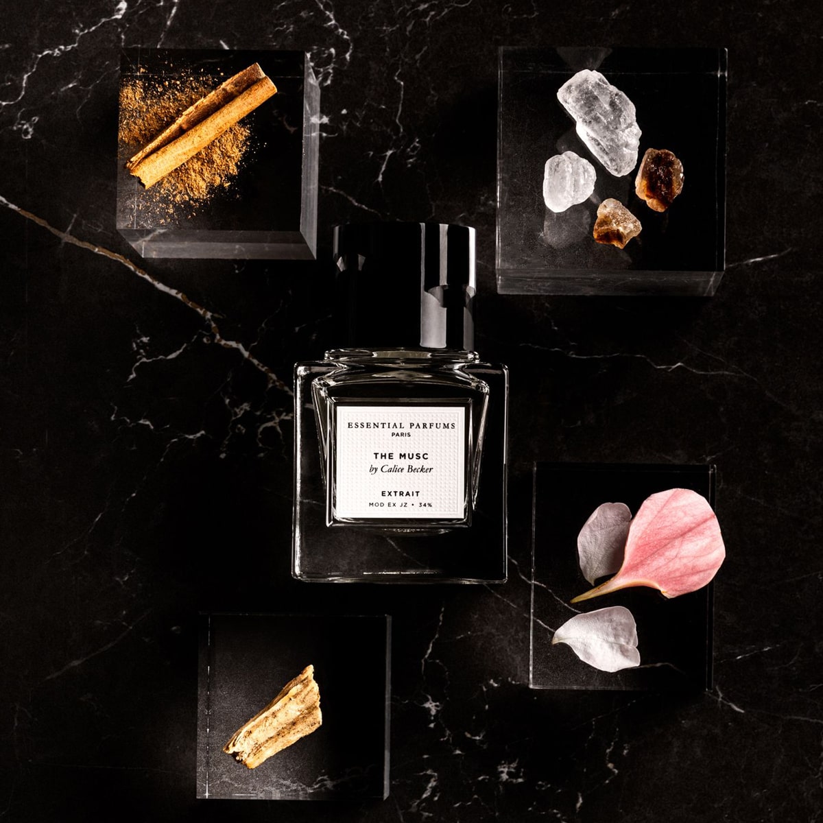 Essential Parfums The Musc Extrait De Parfum by Calice Becker (30 ml) on a dark marble surface with decorative elements and ingredients