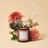 Rifle Paper Co. Clementine & Clove Glass Candle (9.5 oz) with flowers in the background of candle