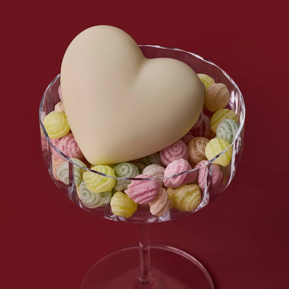 Kate McLeod Sweet Blossom Heart-Shaped Lotion Bar (3.18 oz) - product shown in glass with candies on red background. 