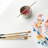 Breathe People Paintbrush Set (5 pcs) - product shown on counter in use with paper and ceramic dish (ceramic dish and paper not included).