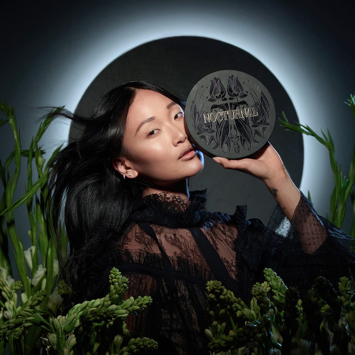 Heretic Parfum Nocturnal Discovery Set (3 pcs) - product shown being held in front of plants and moon in background.