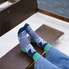 Model wearing Donna Wilson Limited Mermaid Socks (1 pair) on a wooden bench with water in the background