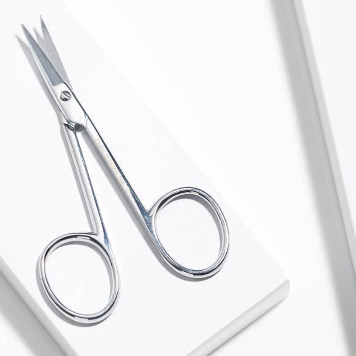 Tweezerman Cuticle Nail Scissors (1 pc) - product shown on white table. 