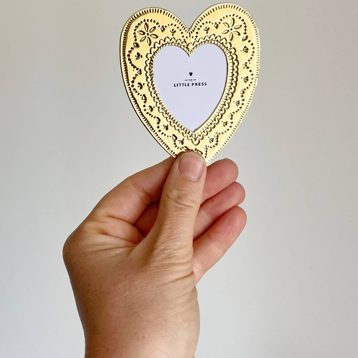 The Little Press Faux Tin Heart Frame - Gold (1 pc) - product shown being held up by hand. 