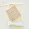 The Quiet Botanist Coconut Soap Bar (4 oz) - product shown on top of cloth bag. 