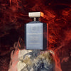 Lifestyle shot of Ormonde Jayne Patchouli d‚ÄôAtlas Eau de Parfum (88 ml) sitting on a rock with crystals and smoke effects in the background