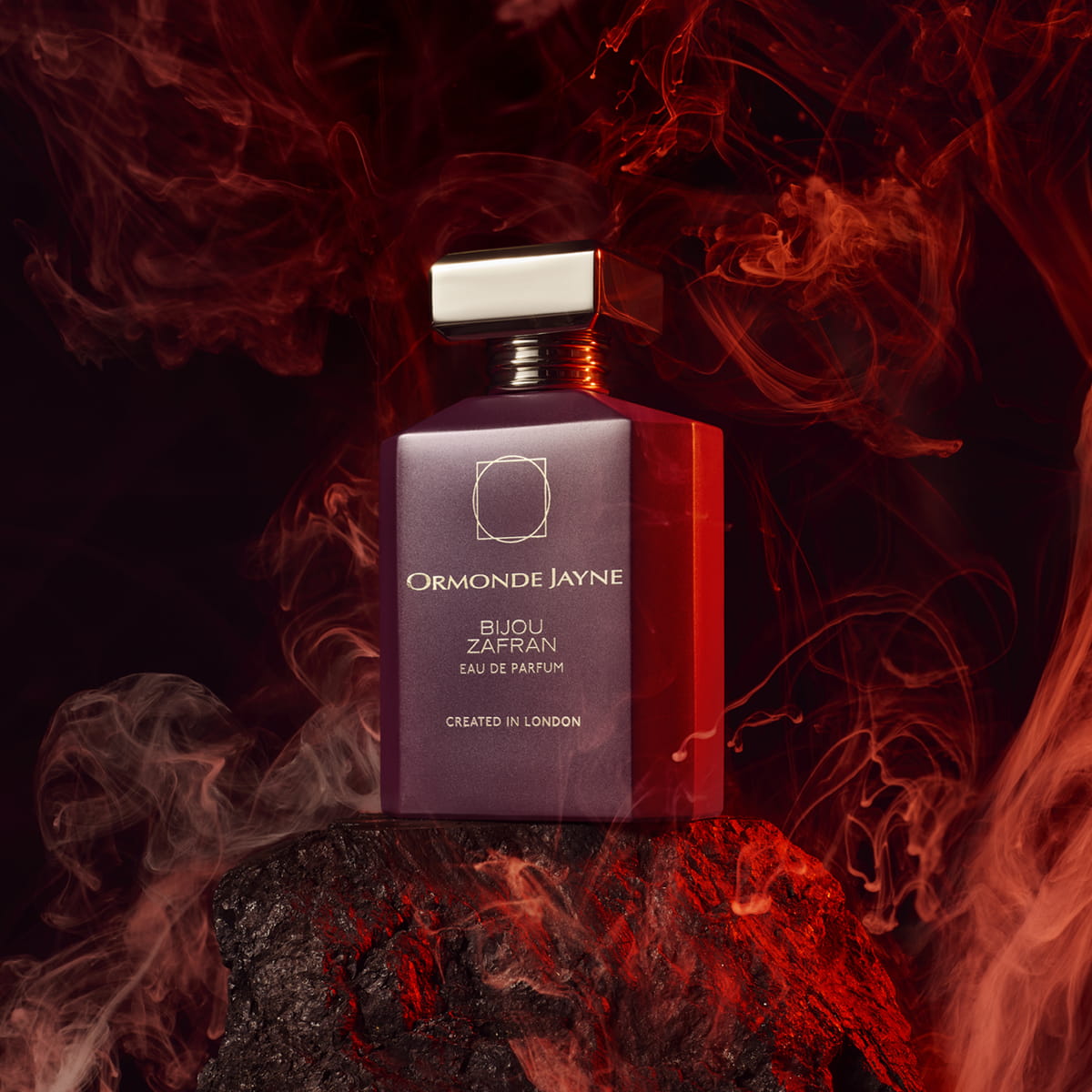 Lifestyle shot of Ormonde Jayne Bijou Zafran Eau de Parfum (88 ml) sitting on rock with smoke effects in the background