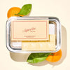 Superfine New York Satsuma Mandarin Creamsicle Vanilla Chocolate Bar (1.76 oz) - product shown on peach colored background with oranges. 