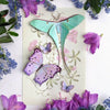 Moth & Myth Hyacinth Moth Set (4 pcs) - product shown in packaging on white counter with colorful flowers. 