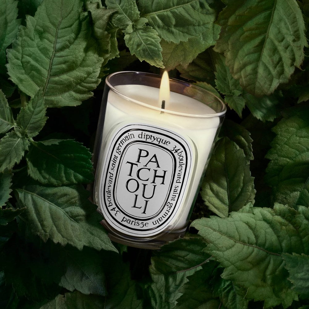 Diptyque Patchouli Classic Candle (190 g)  - product shown on top of patchouli leaves. 