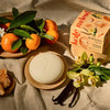 Kate McLeod Tangerine & Vanilla Deep Moisturizing Lotion Bar (3.5 oz) - product shown on table with tangerines and vanilla. 