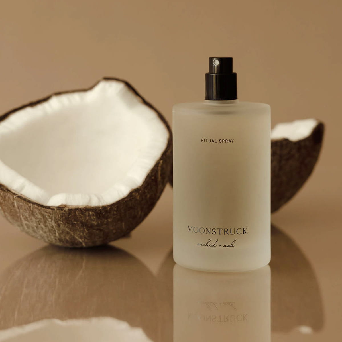 Lifestyle shot of Orchid + Ash Moonstruck Ritual Spray (100 ml) with coconut shell opened against a beige background