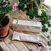 Lifestyle shot of C.Atherley Geranium No.4 Hand Cream (75 ml) with box and geraniums in pots in the background