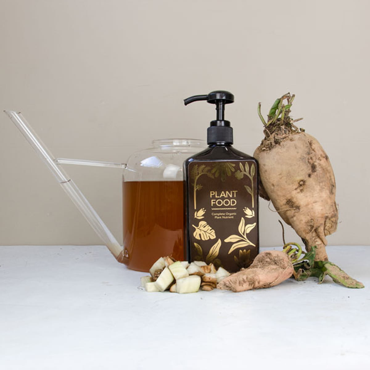 Botanopia Complete Organic Plant Food (450 ml) - product shown next to plants and glass water-bucket. 